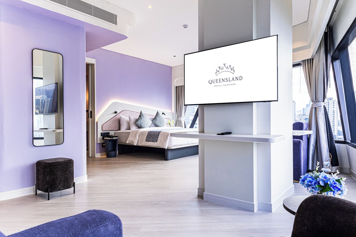Une chambre d’hôtel moderne, équipée d’un lit, d’une télévision et d’une grande fenêtre.
