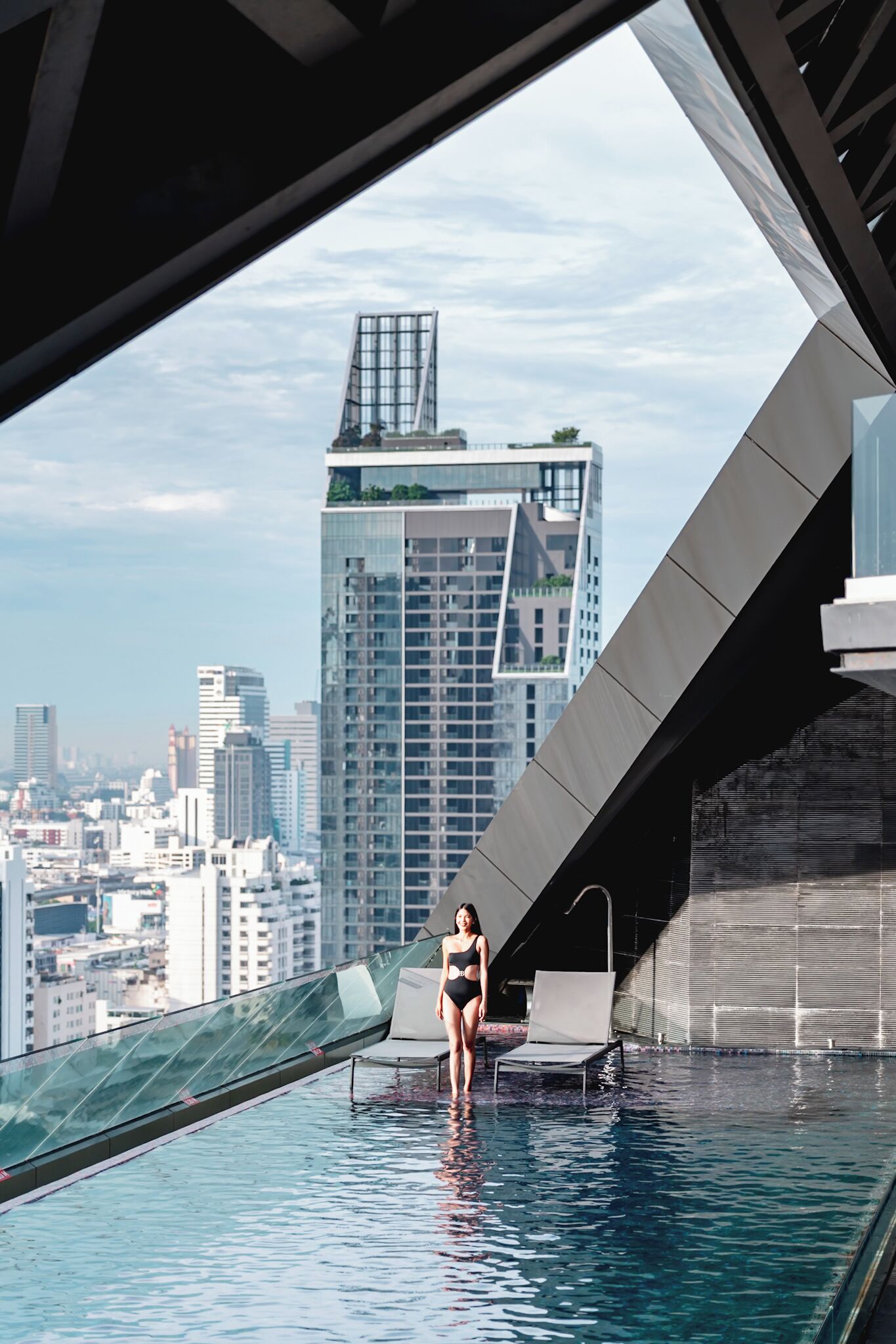 Une piscine moderne située sur le toit, offrant une vue sur le paysage urbain, dotée d’une balustrade en verre et présentant un design architectural contemporain.