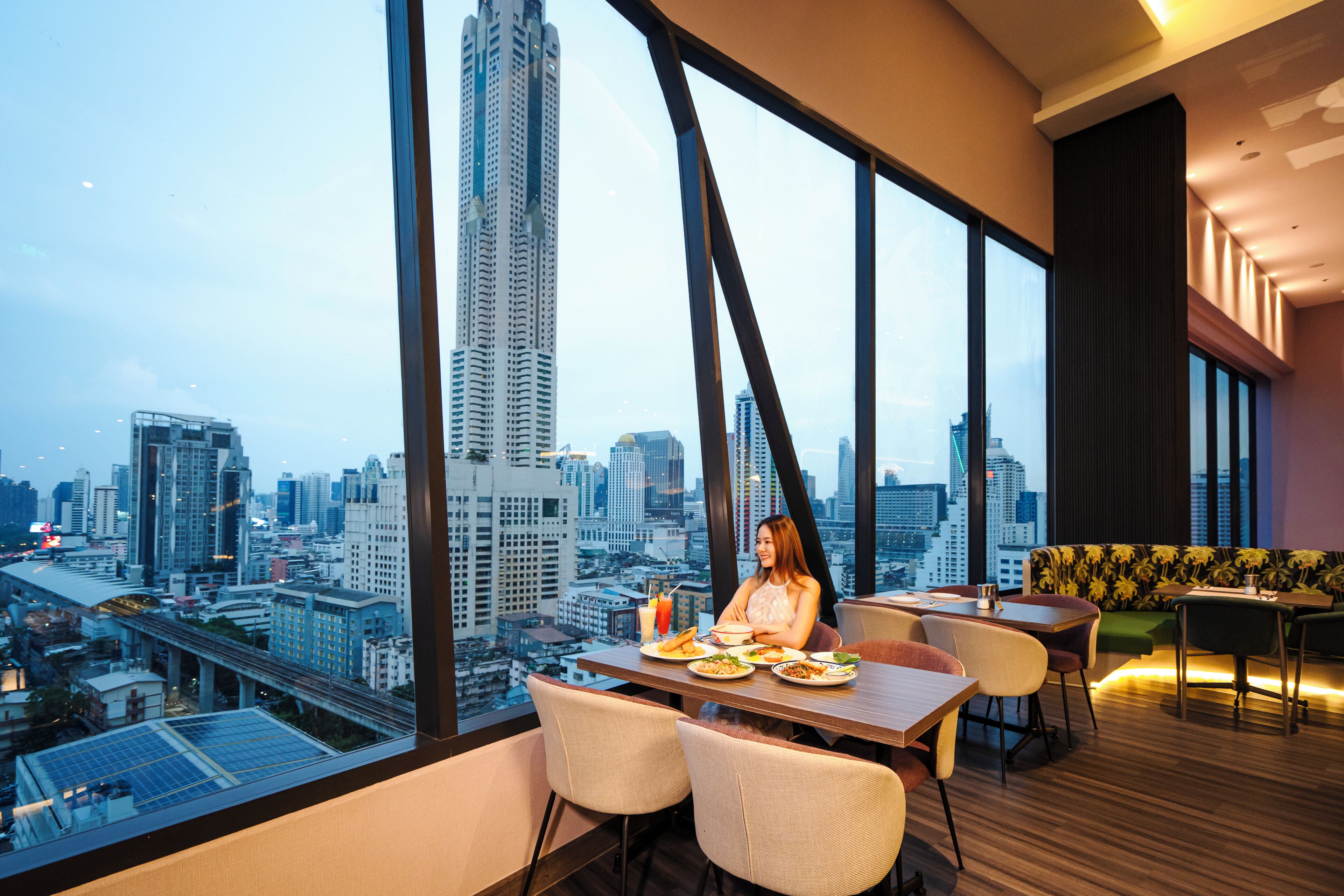 A modern dining area with a city view, featuring a high-rise building in the background.