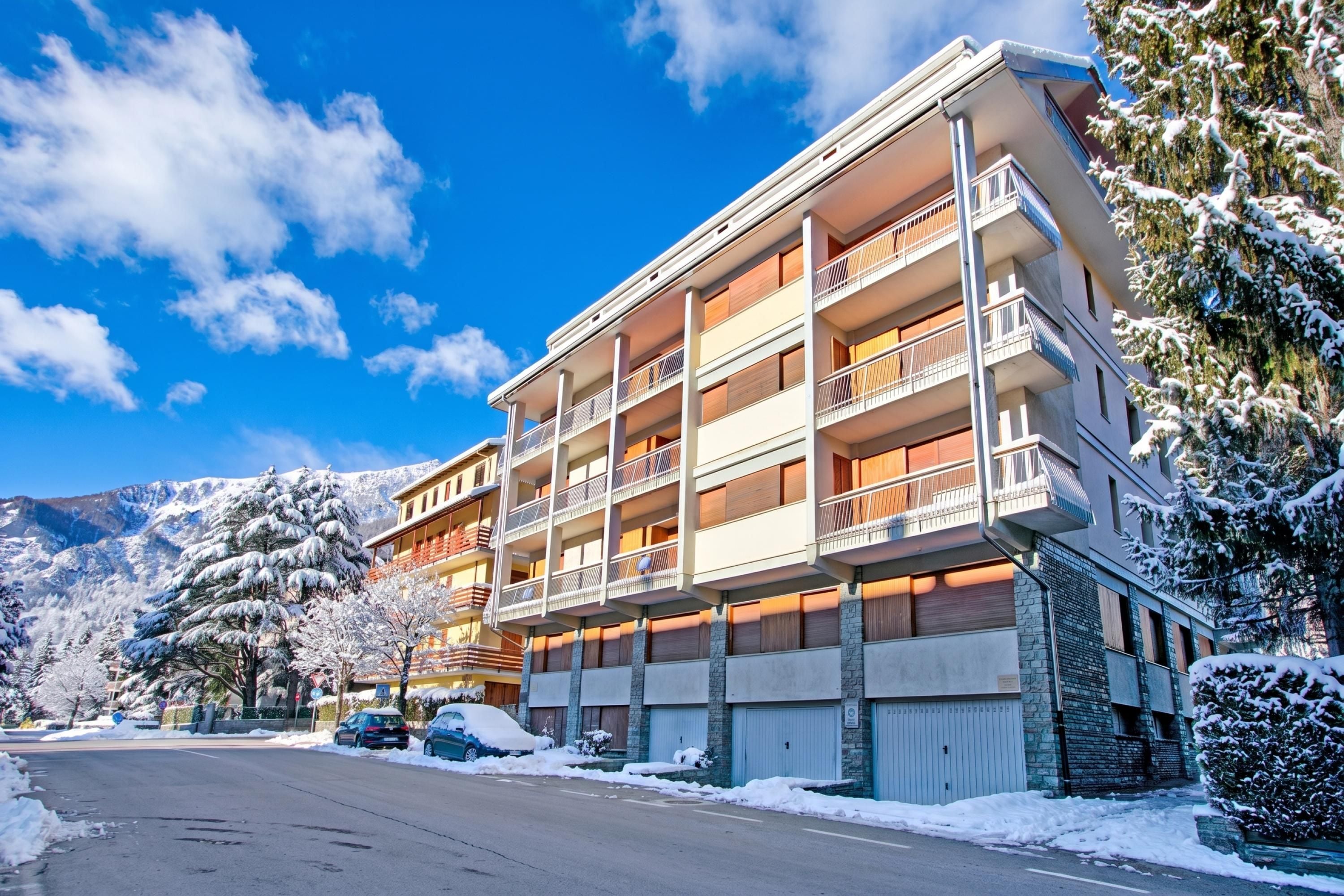 Ein mehrstöckiges Hotel mit Balkonen, einem Parkplatz und verschneiter Umgebung.