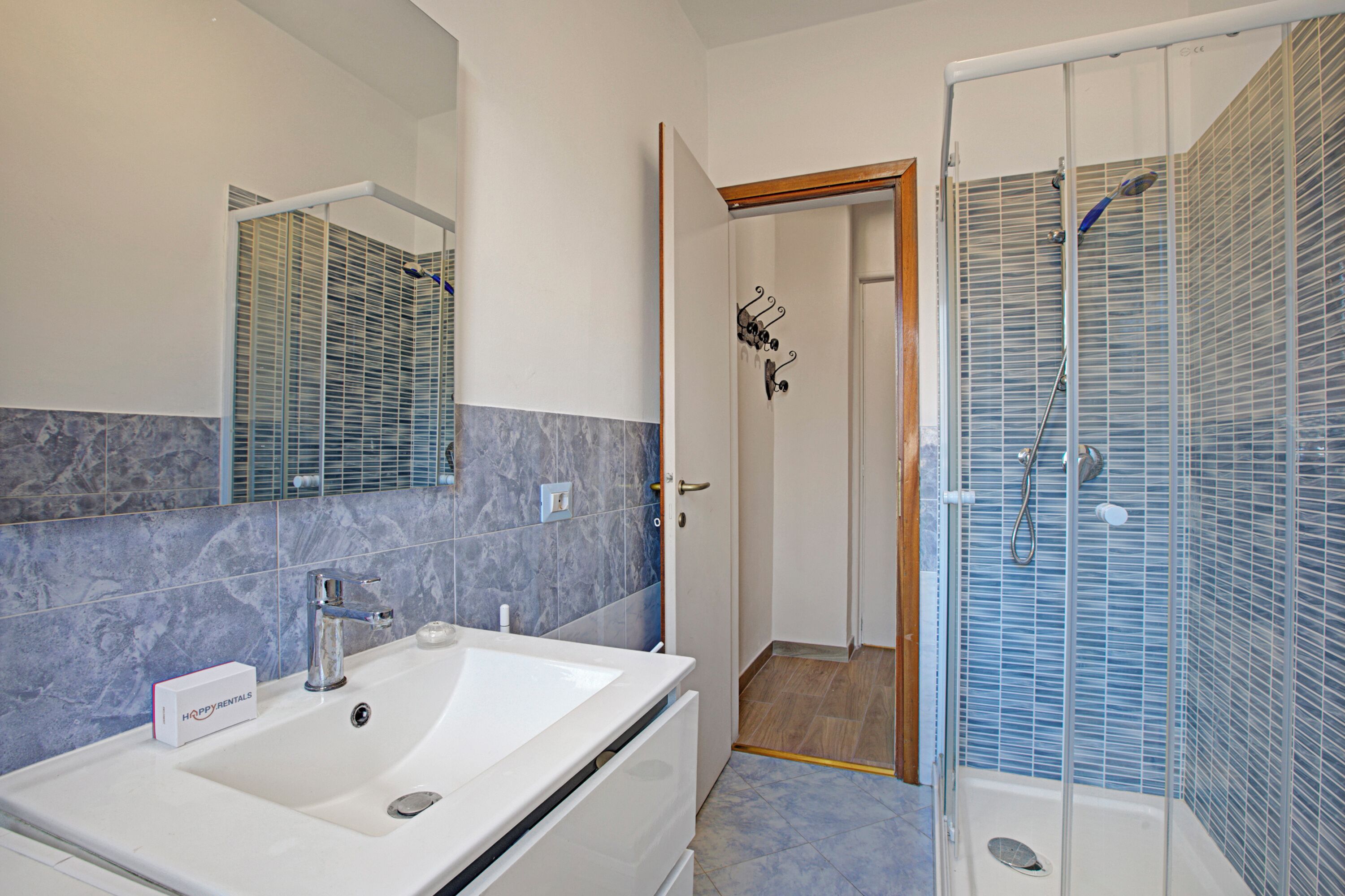 A bathroom with a white sink, a mirror, and a shower enclosure.