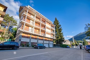 A multi-story building with balconies, parked cars, and a mountainous backdrop. - La Casa Di Felice (Bardonecchia)