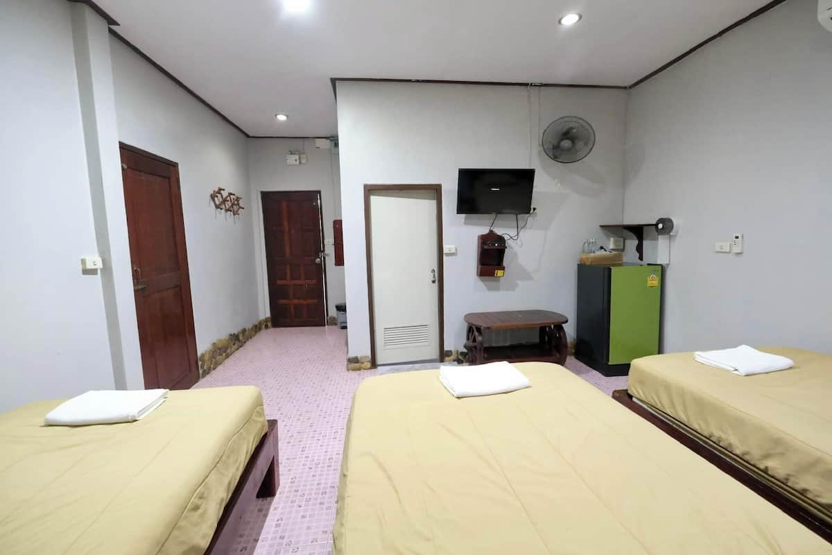 Une chambre d’hôtel avec deux lits, une télévision, un ventilateur et une petite table.