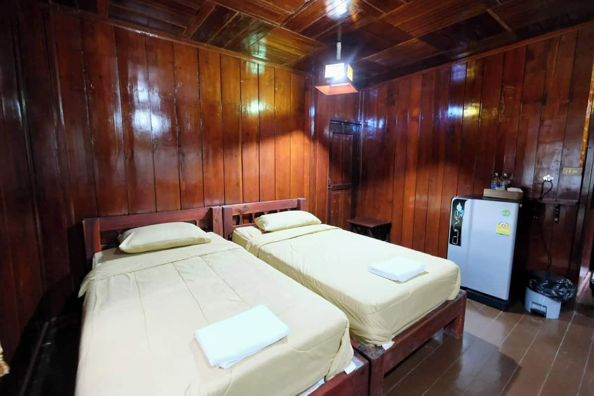 Une pièce aux murs en bois, avec deux lits recouverts de draps beiges.
