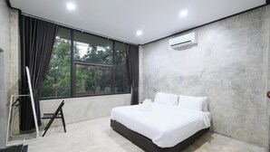 Ein modernes Schlafzimmer mit einem großen Bett, einem Fenster mit Vorhängen, einer Wand-Klimaanlage und einem Betonboden.