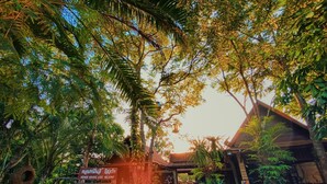 Der Eingang eines Resorts mit einem Schild, umgeben von üppiger Vegetation und einem traditionellen Holzgebäude.