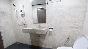 Ein Badezimmer mit Marmorwaschbecken, Duschbrausehandstück, Toilette und Spiegel.