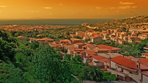 A coastal town with terraced houses and a prominent hilltop structure. - Casa Simona (Sennori)