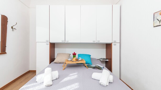A bedroom with a bed, a wooden tray with breakfast items, a magazine, and towels. - Casa Simona (Sennori)