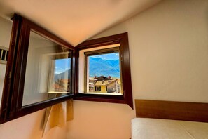 A room with a window overlooking a mountainous landscape.