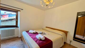 Habitación de hotel con cama, ventana, radiador y candelabro.