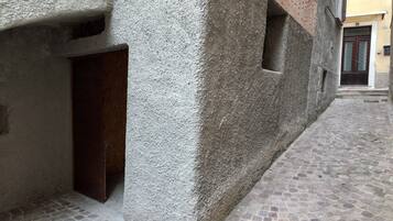 Un estrecho callejón con pavimento de adoquines, una pared con textura y una puerta de madera.