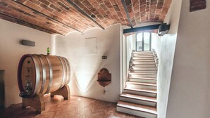 A room with a wooden barrel, a brick ceiling, a herringbone floor, and a staircase leading to another level.