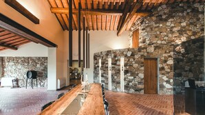 A spacious room with a long wooden table, stone walls, and a herringbone floor pattern.