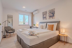 A modern bedroom with a large bed, bedside tables, a chair, and artwork on the walls. - Vipava River Retreat Jacuzzi & Garden (Vipava)