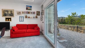 Ein modernes Wohnzimmer mit einem roten Sofa, einem Flachbildfernseher und einem Bücherregal voller Bücher und Dekoration.