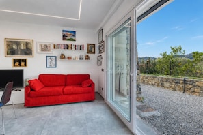 A modern living room with a red sofa, a flat-screen TV, and a bookshelf filled with books and decorative items. - Gemma Marina Near Villa Grock Museum (Imperia)