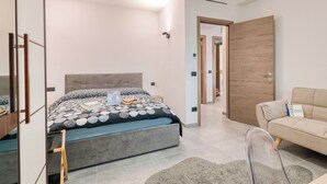 A modern bedroom with a bed, a sofa, and a wooden wardrobe. - Gemma Marina Near Villa Grock Museum (Imperia)