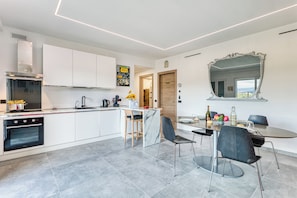 A modern kitchen with white cabinets, a built-in oven, and a marble island.