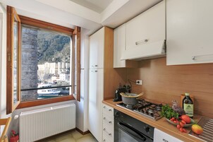 A kitchen with a view of a mountain, a stove, a sink, and cabinets.
