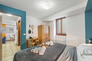 A hotel room with a bed, a desk, a chair, and a wardrobe.