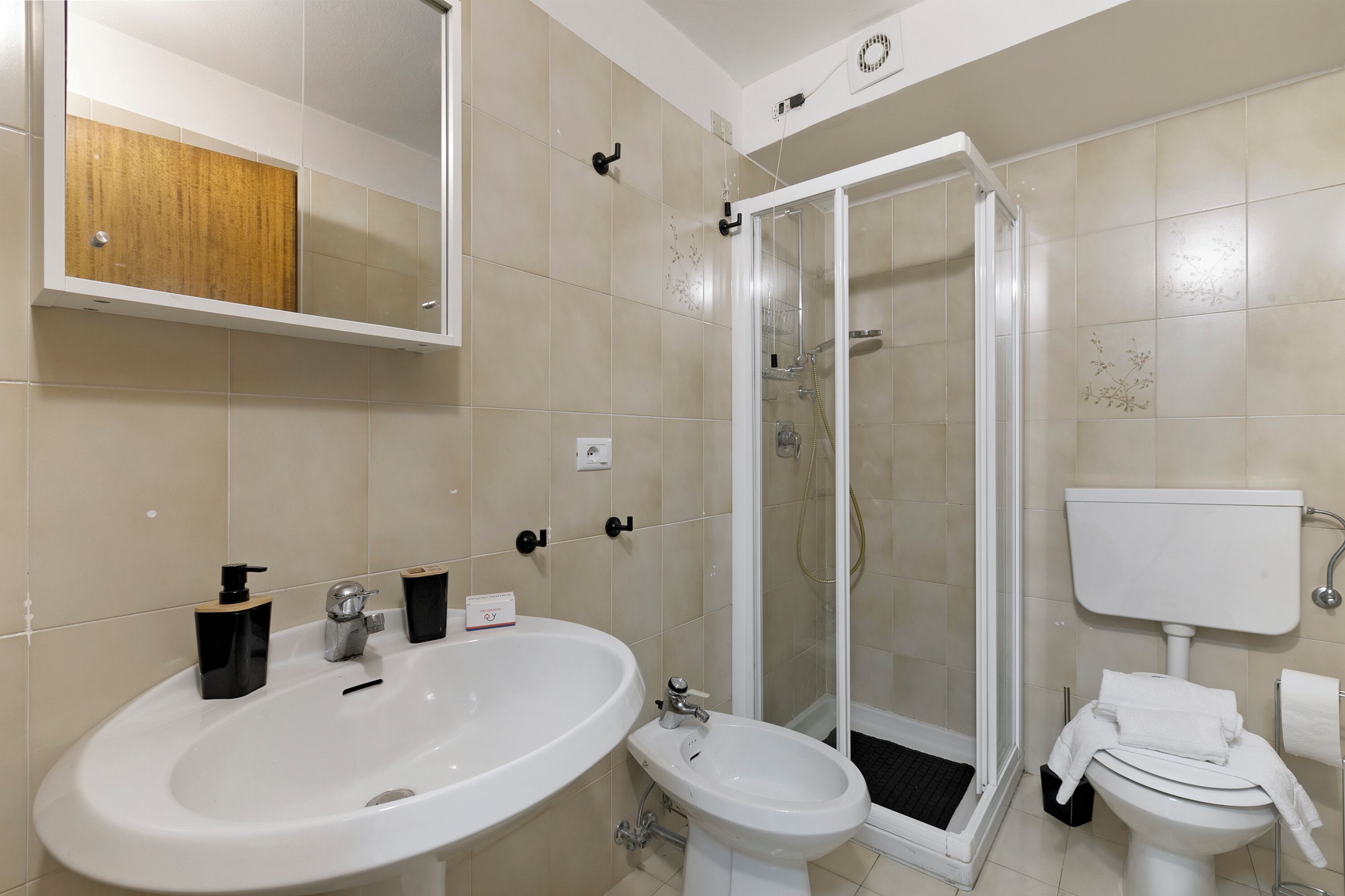 A bathroom with a sink, bidet, toilet, and glass-enclosed shower.