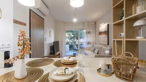 Ein modernes Wohnzimmer mit Essbereich, ausgestattet mit einer Couch, einem Fernseher und einem Bücherregal.