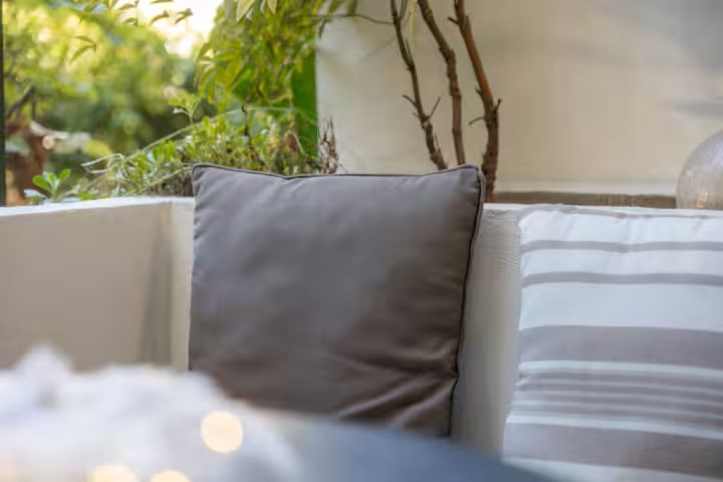 A close-up of a room with a grey pillow and a striped pillow on a white sofa.