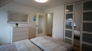 A bedroom with a bed, a dresser, a mirror, and a wardrobe. - Ferienhaus in Busum fur 4 Personen (Büsum)