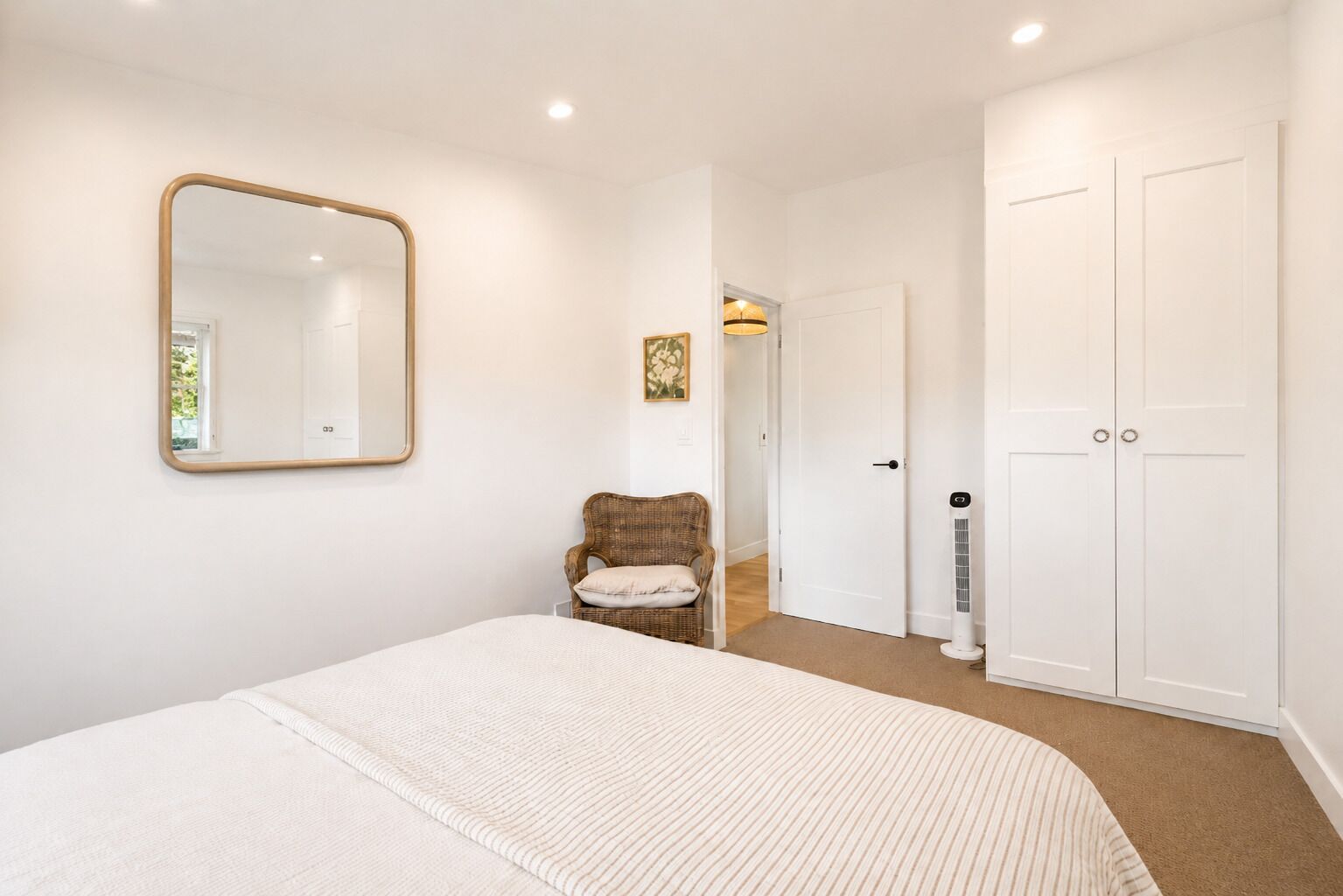 A bedroom with a bed, a chair, a wardrobe, and a mirror.