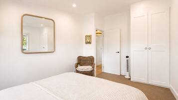 A bedroom with a bed, a chair, a wardrobe, and a mirror.
