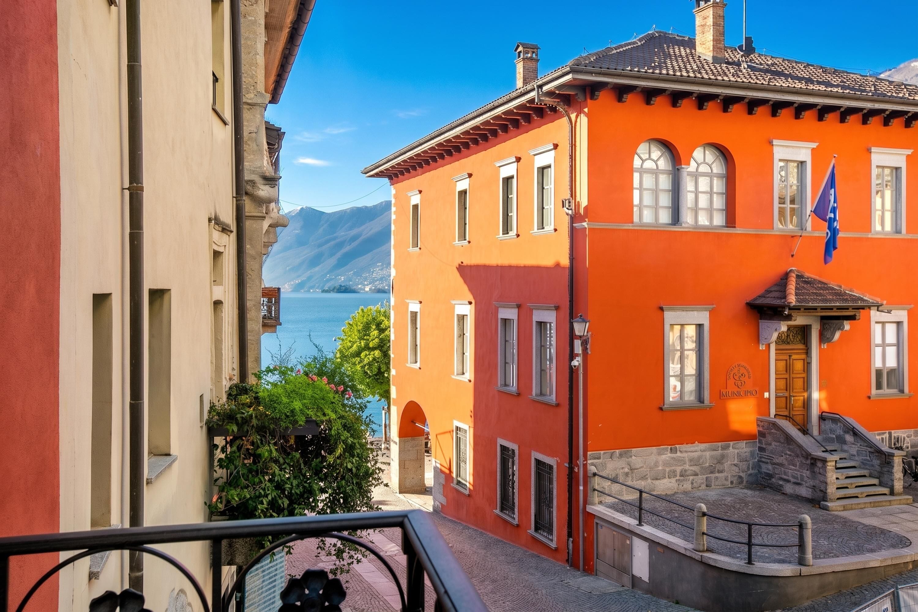 A building with a red facade, a flag, and a view of a lake.