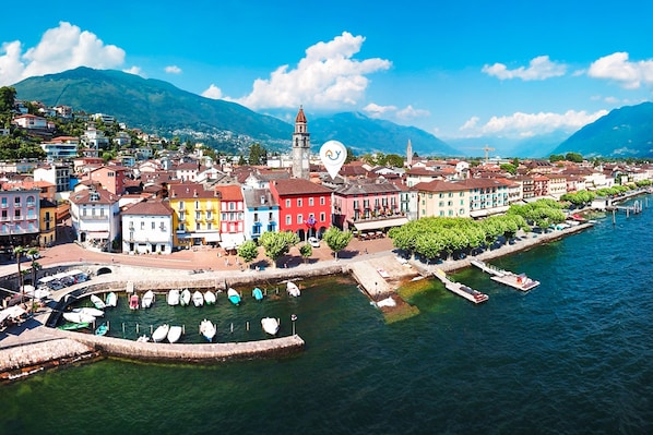 A coastal town with colorful buildings, a prominent tower, and a marina with boats. - Corte di Ascona Apartments (Ascona)