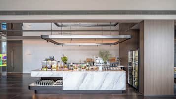 A modern bar area with a marble countertop, various glassware, and a coffee machine.