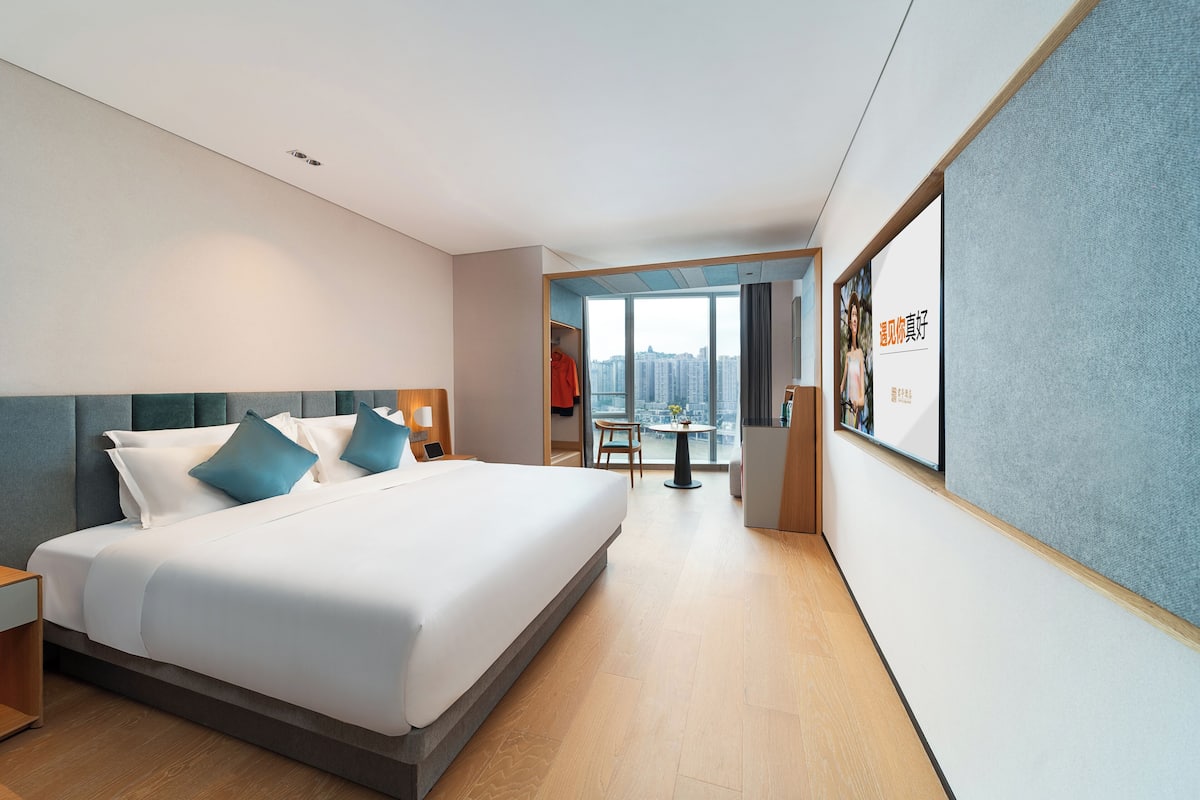 Una habitación de hotel moderna con una cama grande, un escritorio y vistas a la ciudad.
