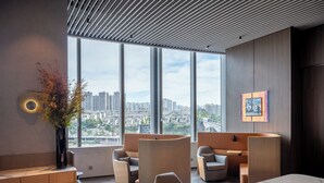 Un espacio de oficina moderno con amplias ventanas, asientos cómodos y vistas a la ciudad.