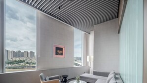 Una sala de estar moderna con un ventanal grande, un sofá, un sillón y una mesa de centro.