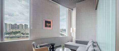 A modern living room with a large window, a sofa, a chair, and a coffee table.