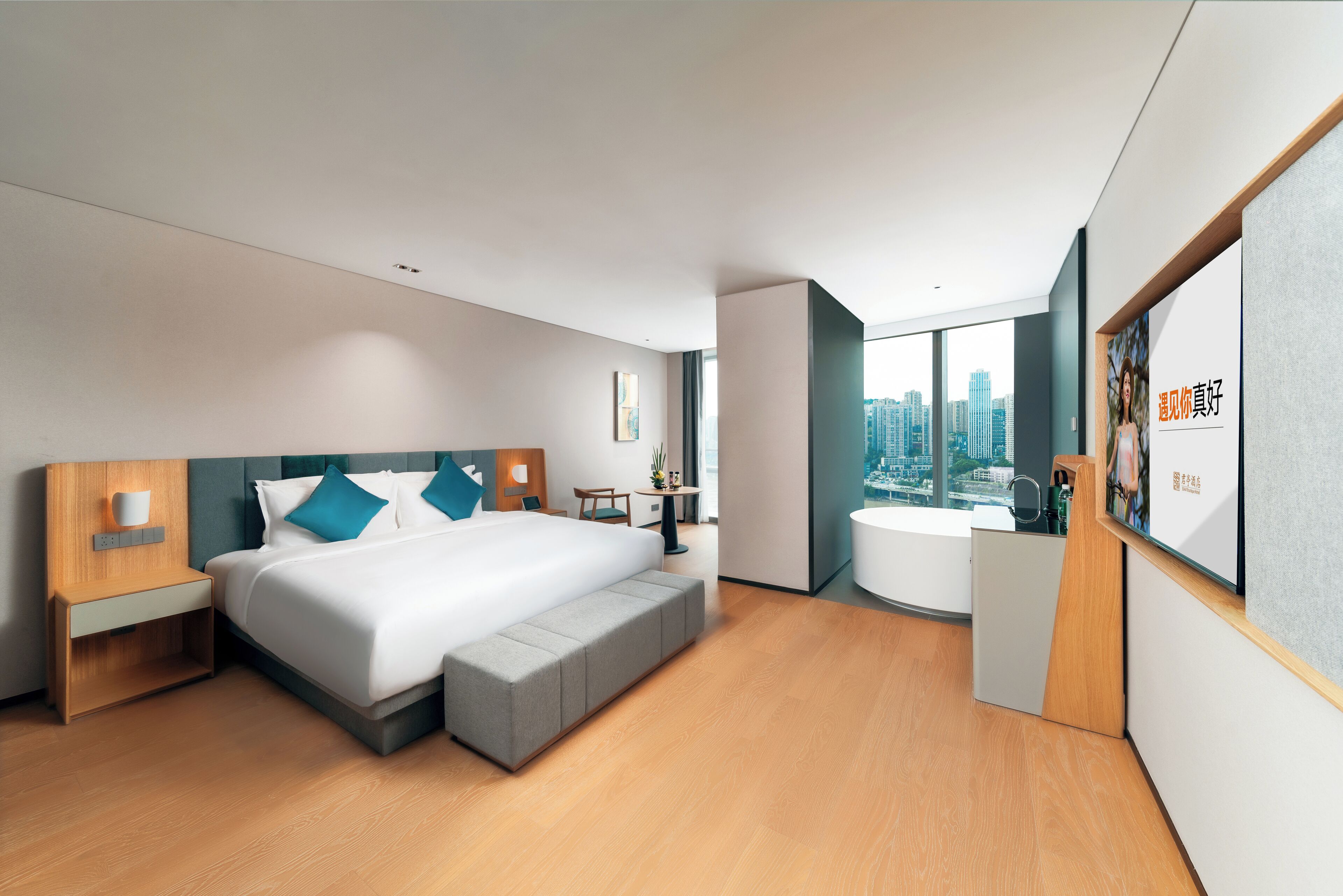 A modern hotel room with a large bed, a desk, a chair, a small table, and a bathtub.