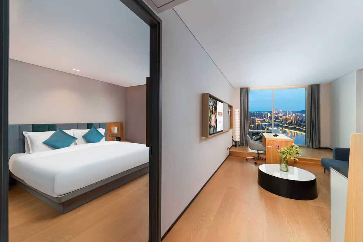 Una habitación de hotel moderna con cama, escritorio y vista a un paisaje urbano.