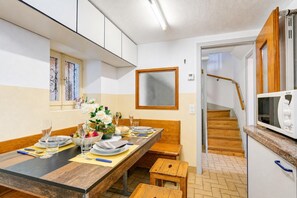 A modern kitchen with a dining area, wooden staircase, and a built-in microwave. - Casa Patrizia Caviano Gambarogno With Lake & Mountain Views (Gambarogno)