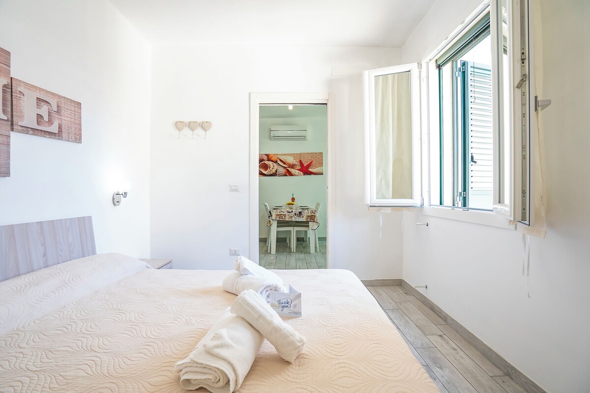 Een hotelkamer met een bed, een raam en uitzicht op een eetruimte.