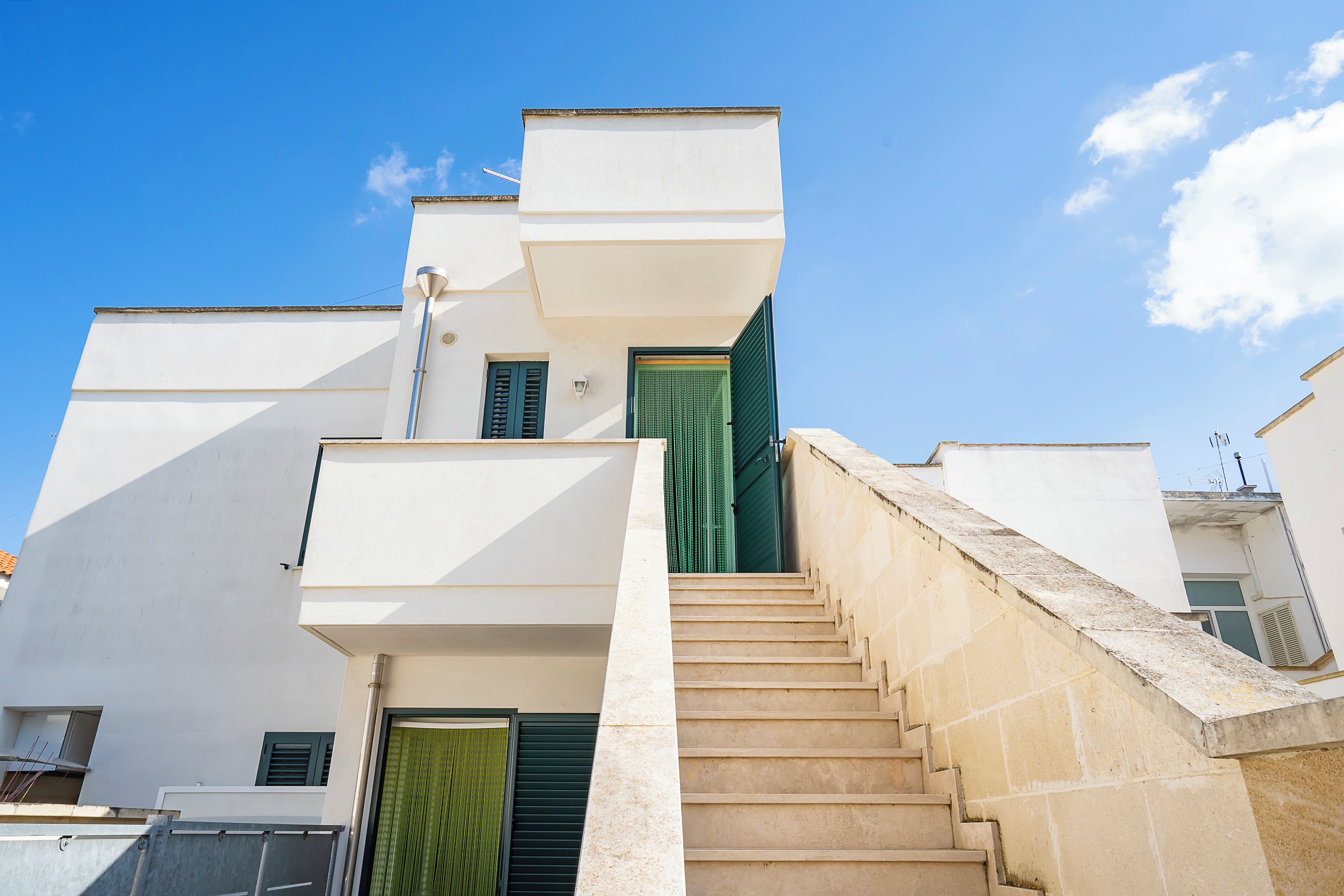 A modern building with a staircase leading to a green door.