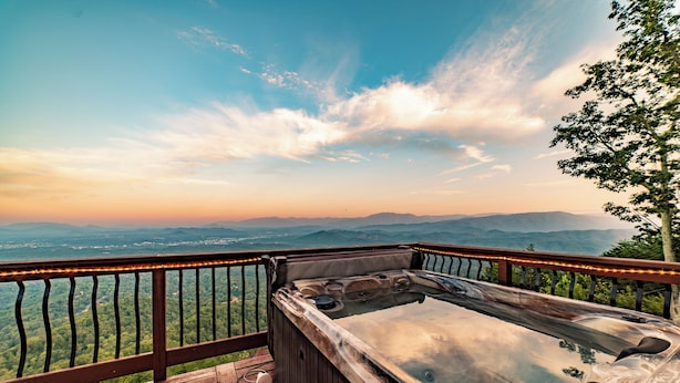 A hot tub on a wooden deck with a view of mountains and a clear sky. - Unparalleled Views, Sauna, Hot Tub, Fire Pit, Game Room | Panorama by AvantStay (Sevierville)