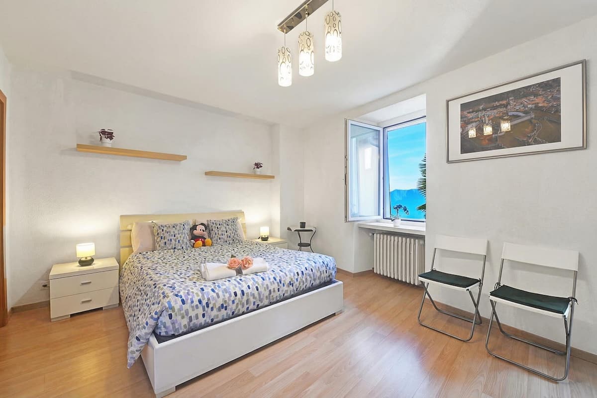 Una camera da letto con un letto, comodini, una finestra con vista e una sedia.