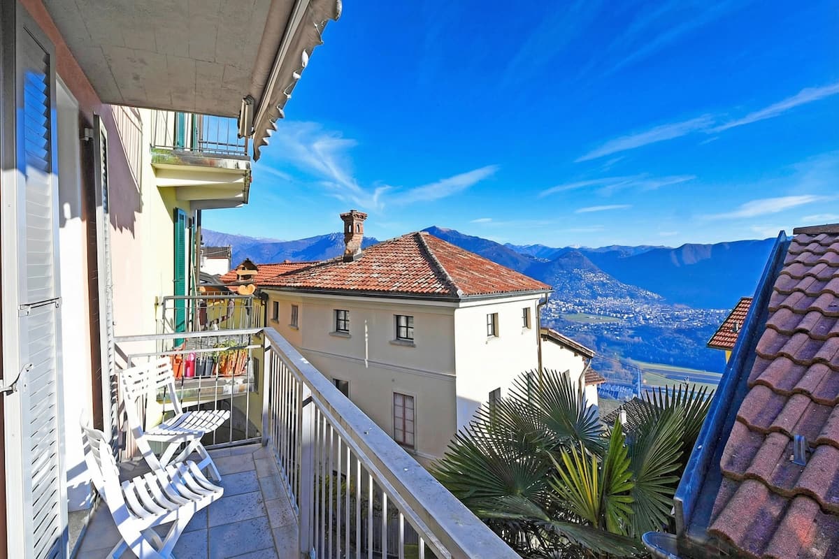 Un balcone con vista sulle montagne, un tetto in tegole e un edificio con un balcone.