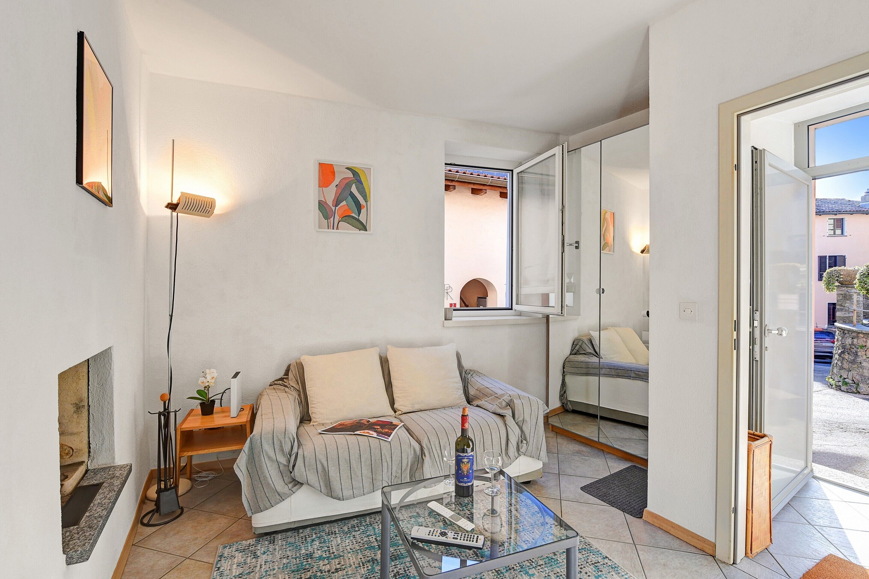 Un salon moderne avec un canapé, une table basse en verre, une cheminée, un téléviseur et un balcon.
