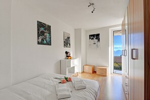A modern bedroom with a bed, white walls, and artwork. - Lugano Bay View (Cademario)