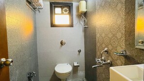 A compact bathroom with a toilet, bidet, and sink. There is a small window above the toilet and a towel rack on the left wall. - hotel abraj inn  (Mumbai)
