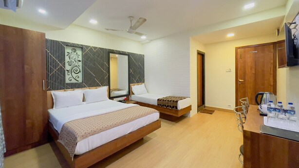 A hotel room with two beds, a wooden floor, a ceiling fan, and a minibar. - hotel abraj inn  (Mumbai)